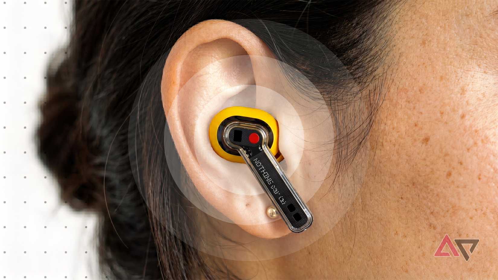 A close-up of a person wearing a yellow Nothing Ear (a) earbud.