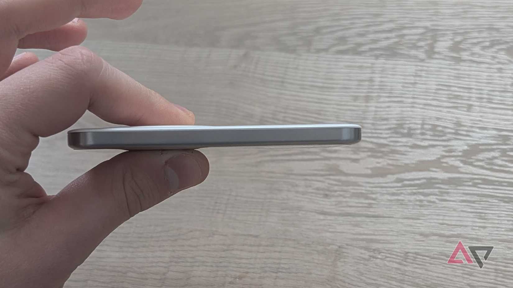 hand holding power bank against wood grain surface