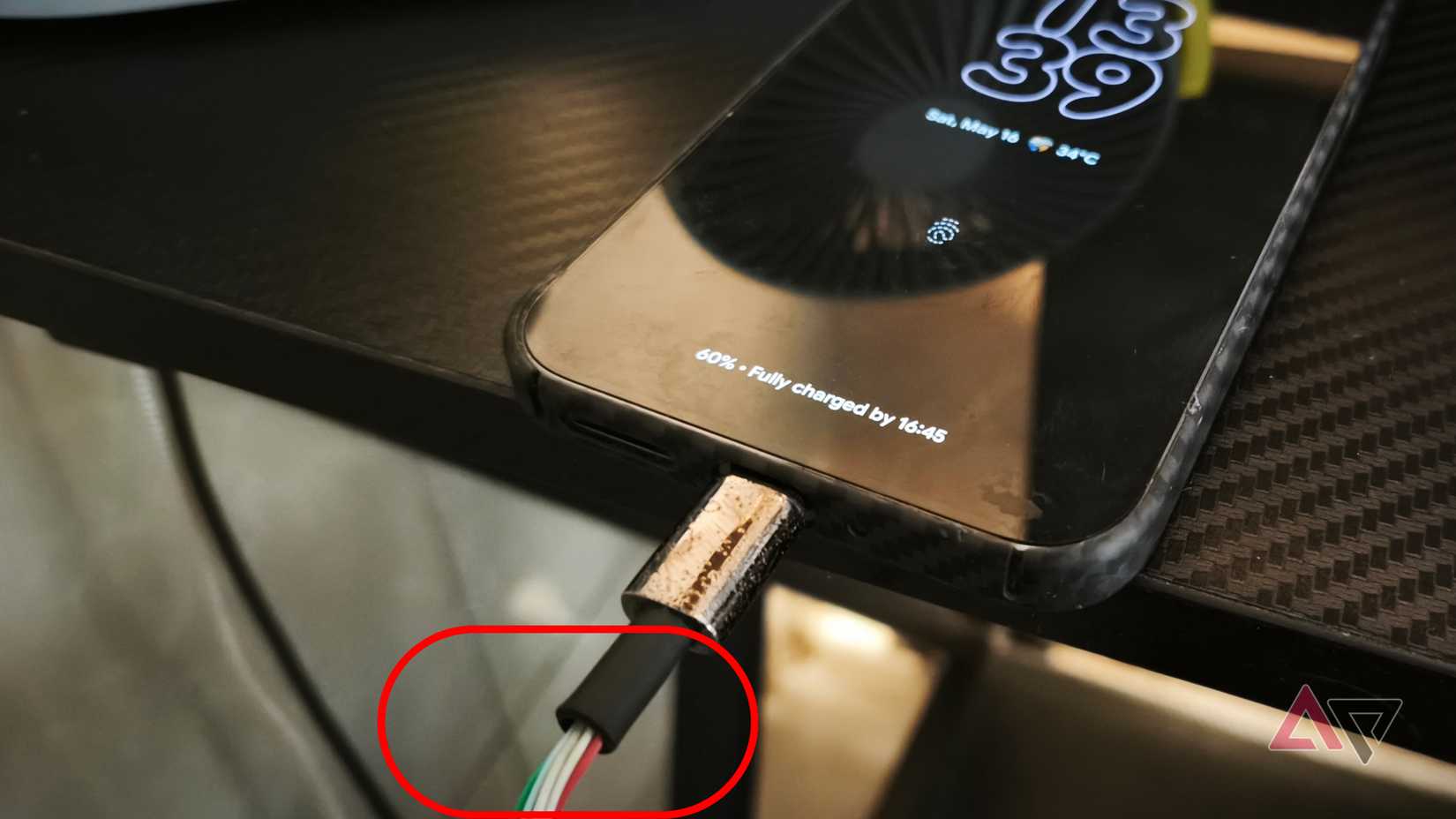 Um cabo/cabo de carregamento mostrado com borracha de retenção danificada enquanto conectado ao smartphone Google Pixel 9 Pro XL