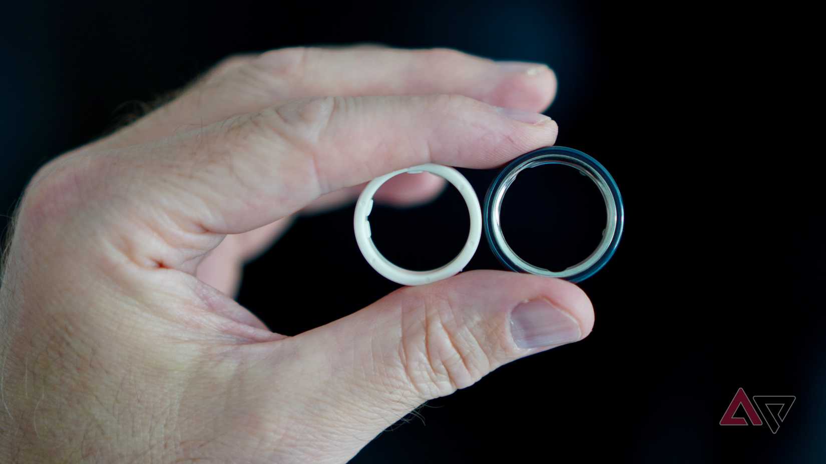 Uma pessoa segurando o Oura Ring 4 e um anel do kit de dimensionamento Oura Ring 5