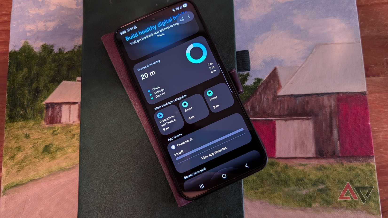 A Samsung Galaxy S25+ device with the google digital wellbeing section showing app timer and limited screen time while sitting on a notebook and painting