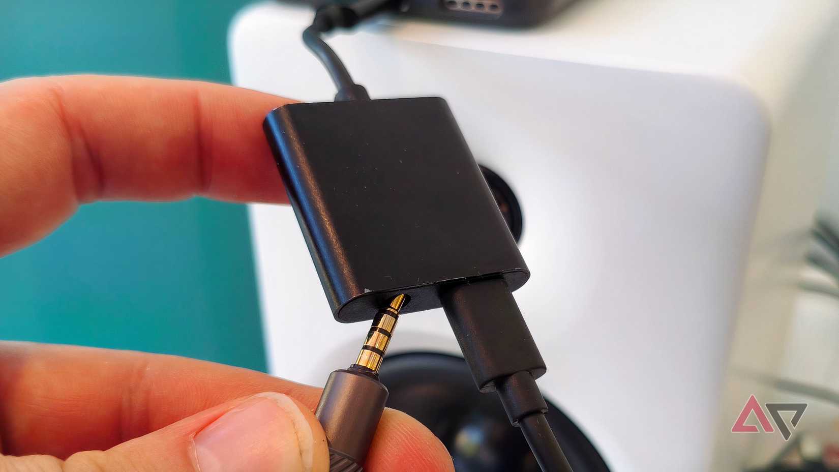 Um divisor USB-C/3,5 mm conectado a um telefone Android, um alto-falante e um carregador.