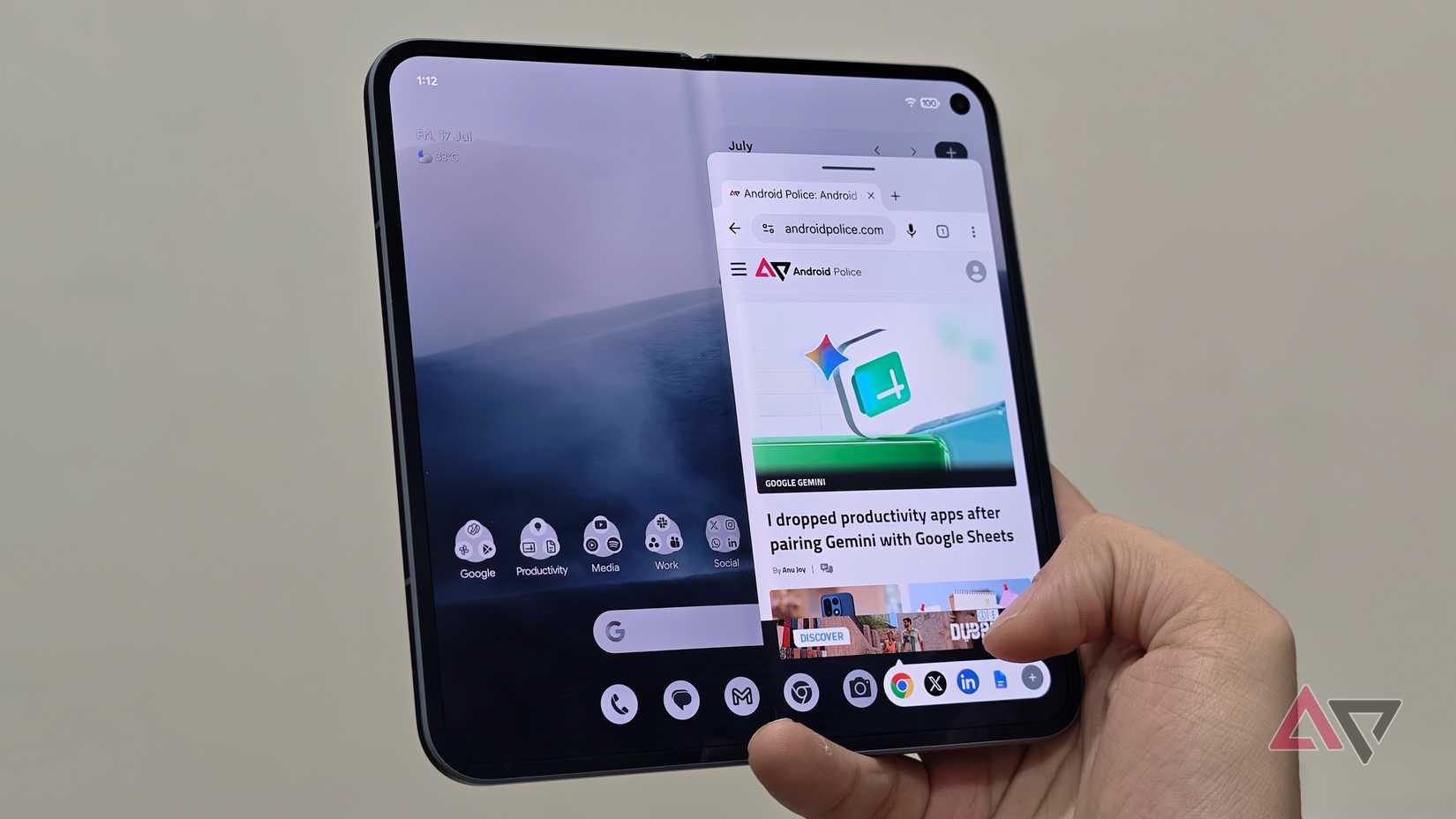 A person holding an unfolded Google Pixel Fold showing a web browser floating window open on the right side of the main display screen