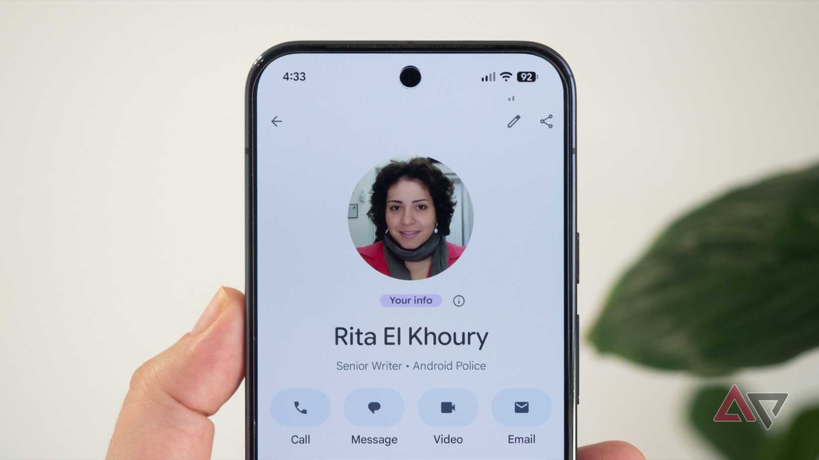 Pixel phone in hand showing Google Contacts personal "your info" card