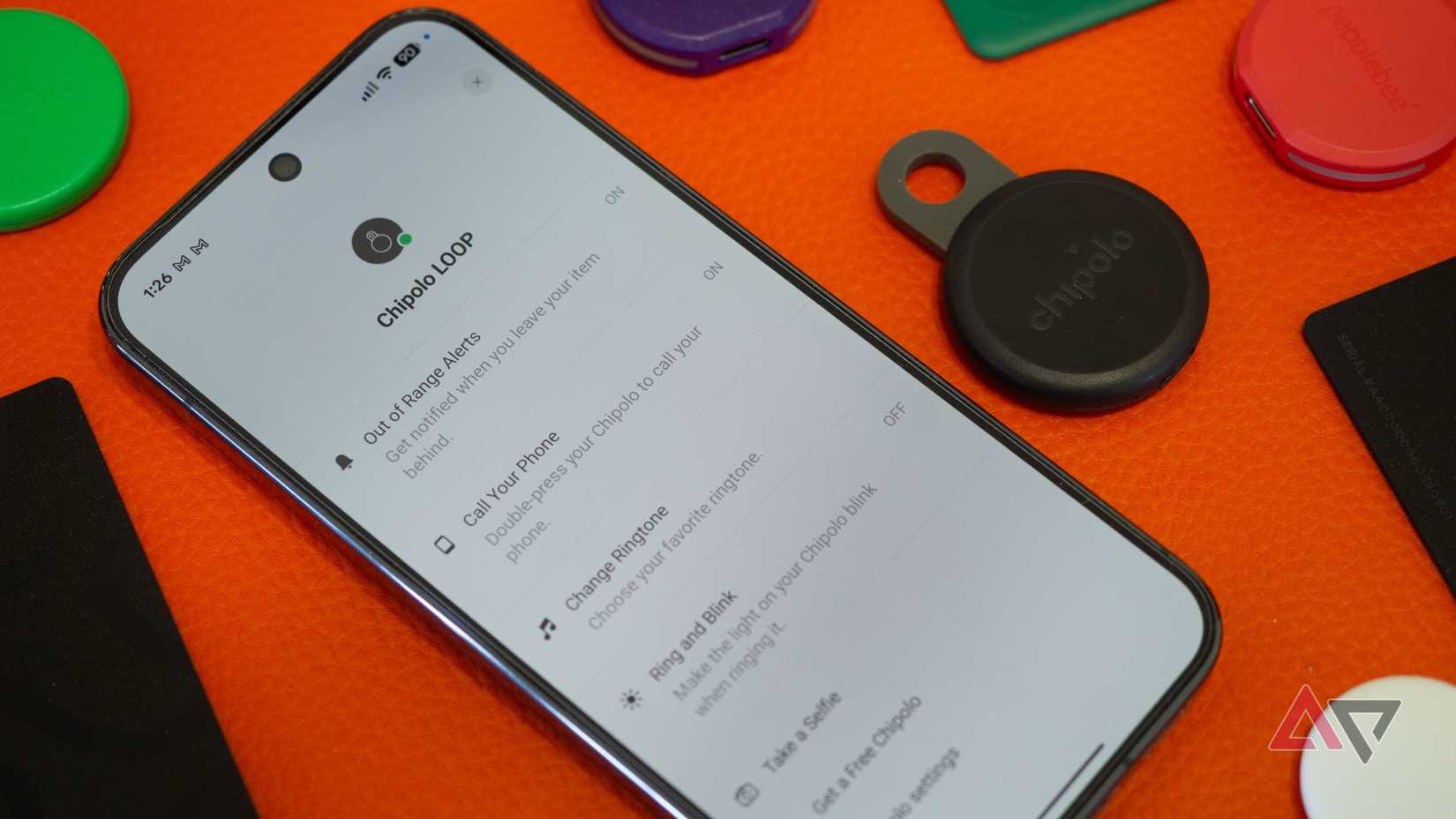 Chipolo Loop Bluetooth tracker next to a phone with the Chipolo app's special extra features