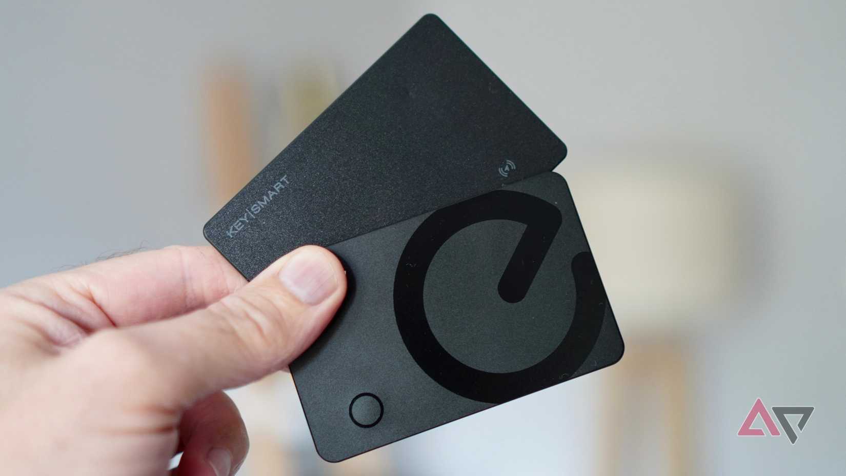 A person holding the Eufy SmartTrack Card E40 and KeySmart Card
