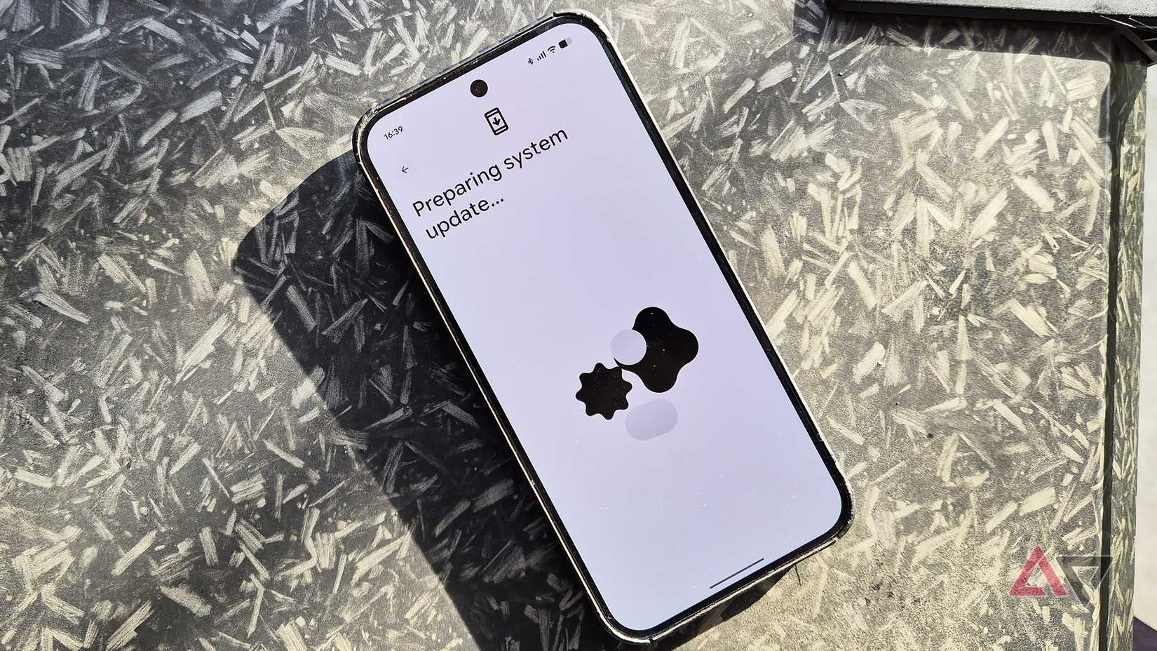 A Google Pixel 9 Pro XL smartphone on a desk showing a software update preparation
