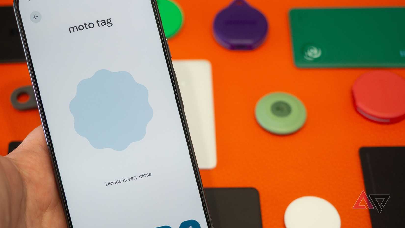 Moto Tag Bluetooth tracker next to a phone with the Google Find Hub's UWB nearby finding activated