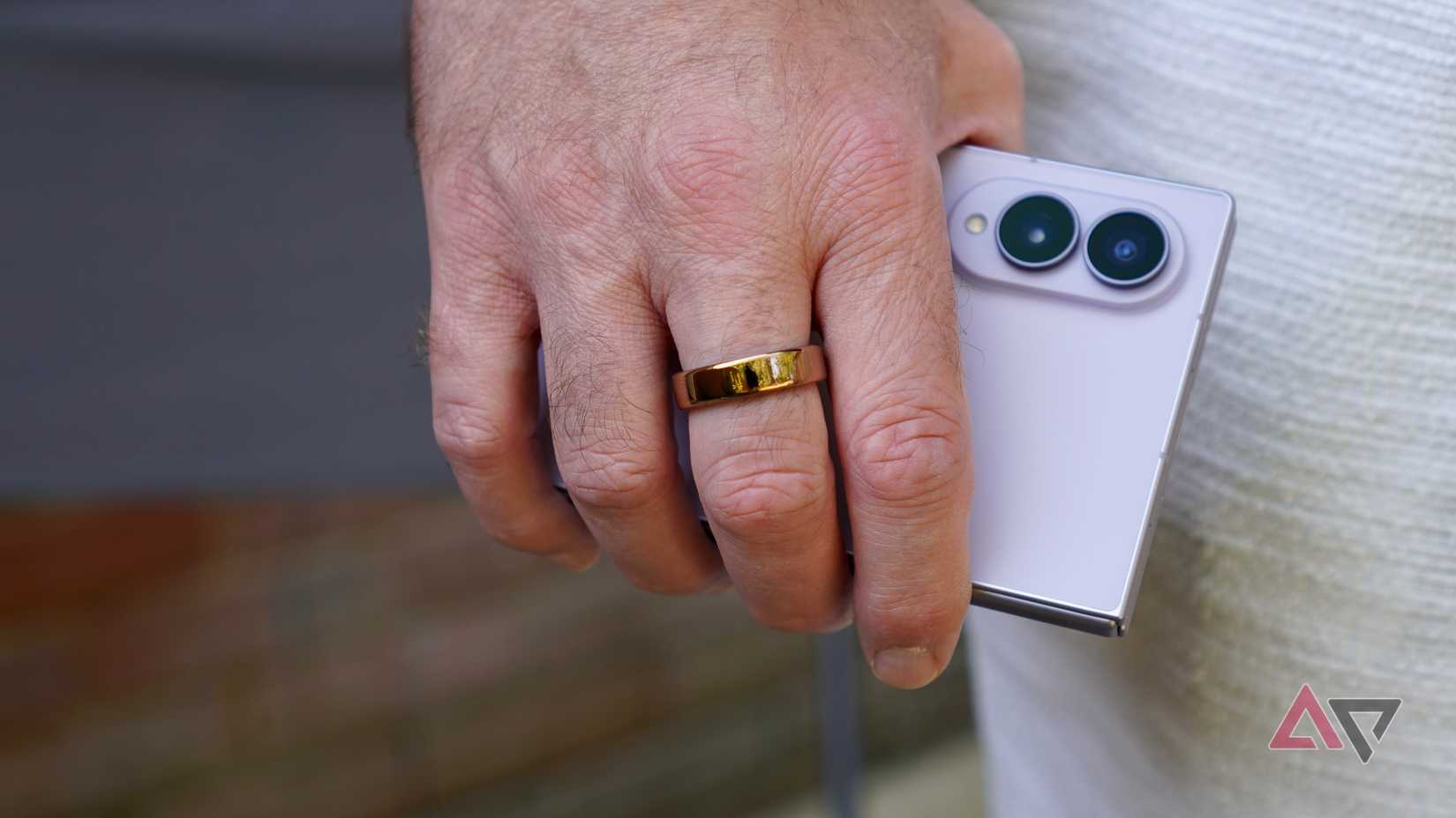 A person wearing the Oura Ring 5 and holding a phone