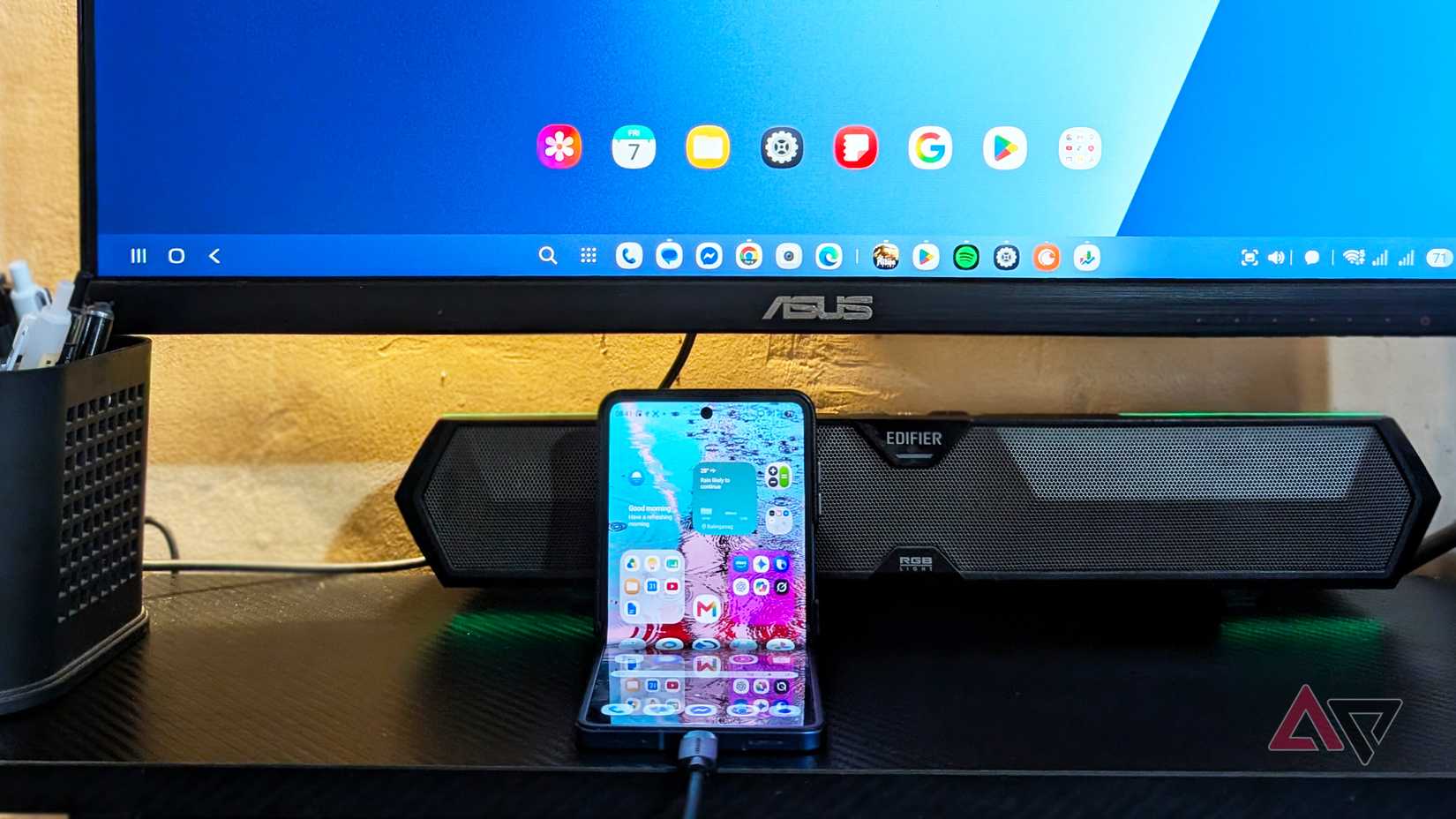 A Samsung Galaxy Z Flip 7 smartphone connected to an external display and speaker via DeX
