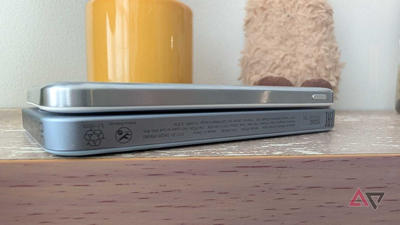 silver power bank lying on top of another on wood surface
