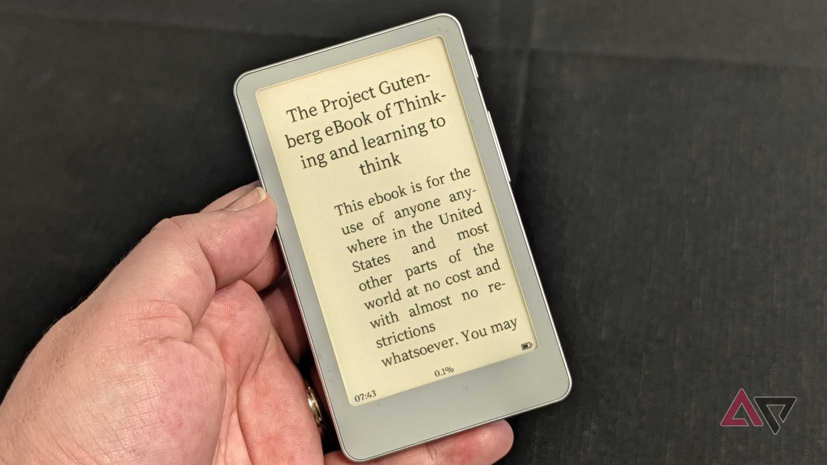 Il Boox Picco in mano accanto a un libro aperto