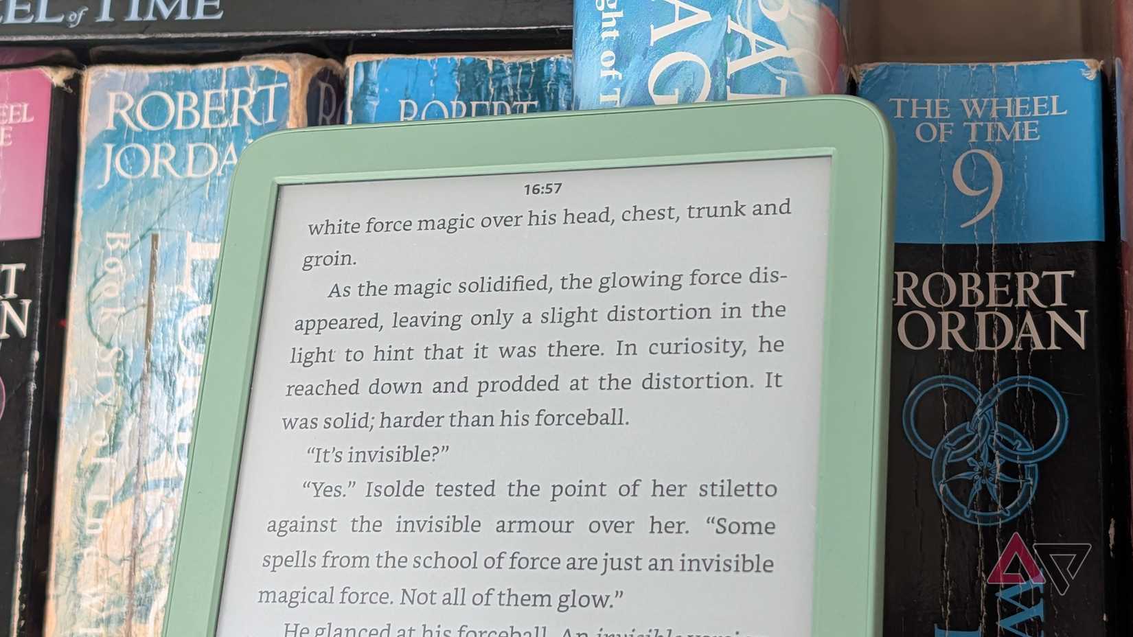 A Kindle leaning against books, with the clock visible at the top of the display.