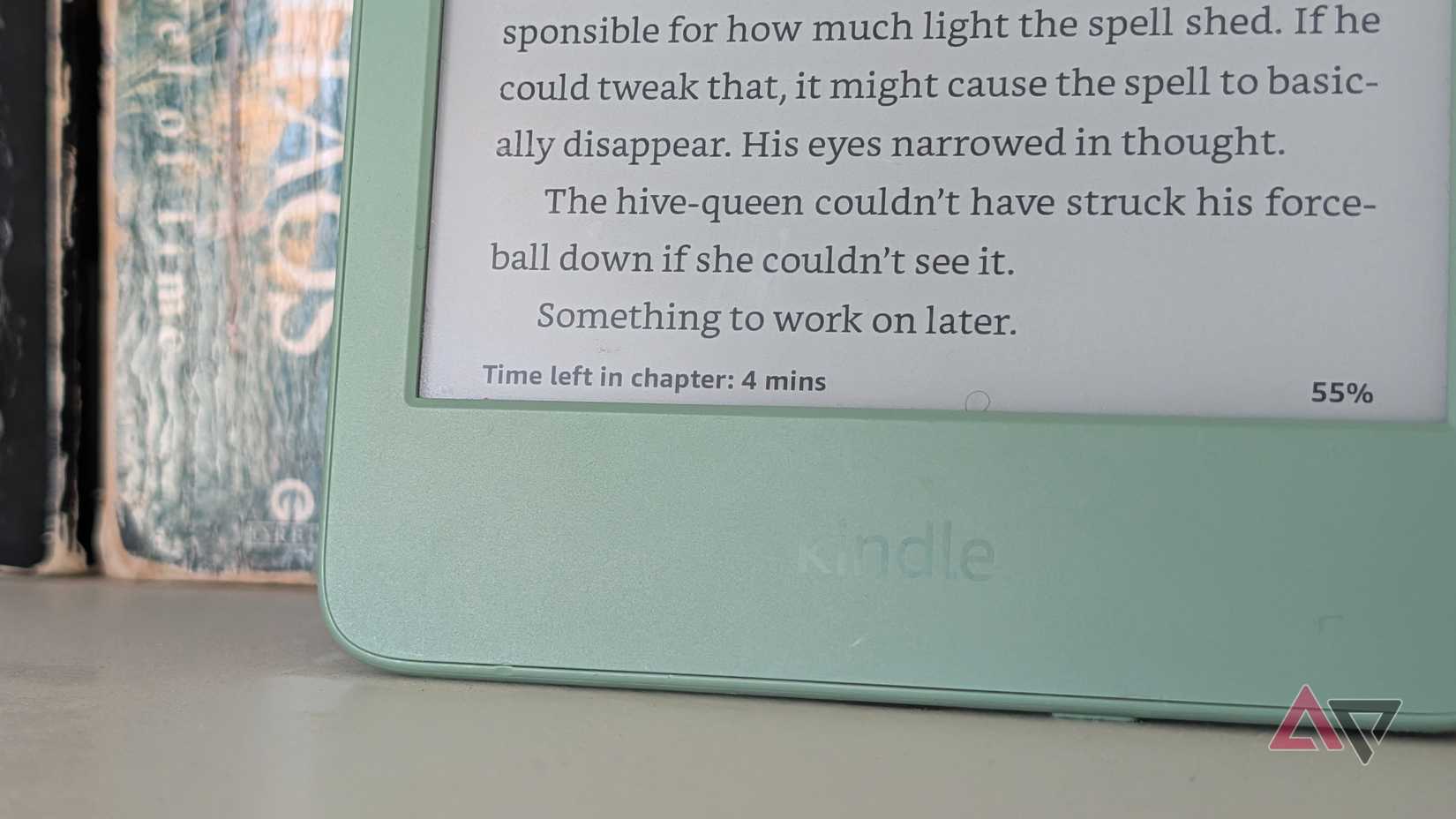 A Kindle leaning against books, with the time left in the chapter visible.
