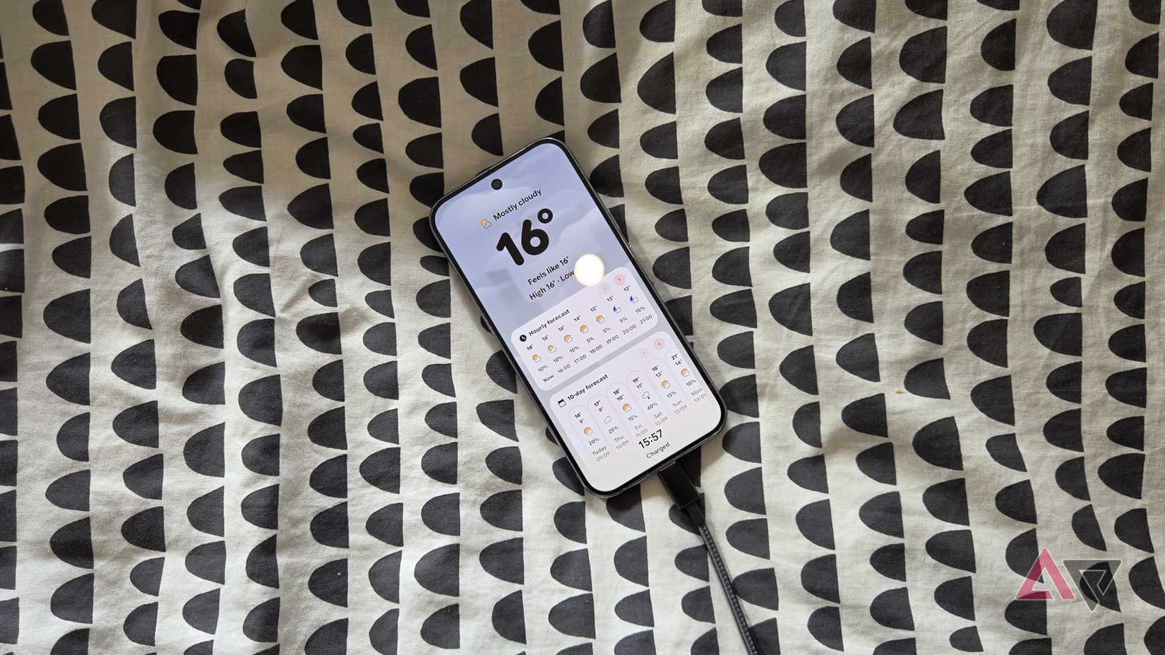 The Pixel 10 Pro on a bedspread, screensaver showing.