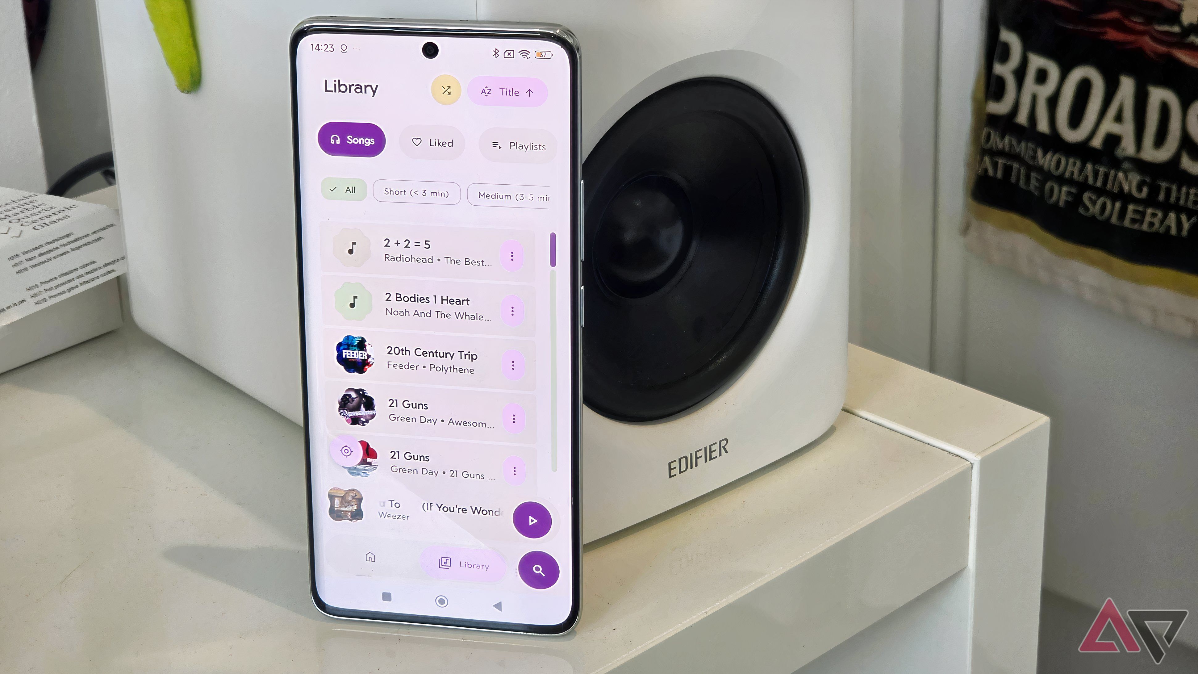 A Poco X7 next to an Edifier M90, showing the Rhythm app with the songs list displayed.