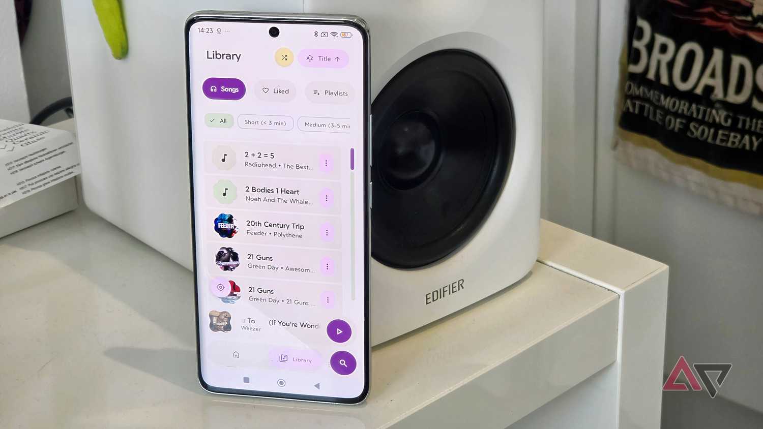 A Poco X7 next to an Edifier M90, showing the Rhythm app with the songs list displayed.