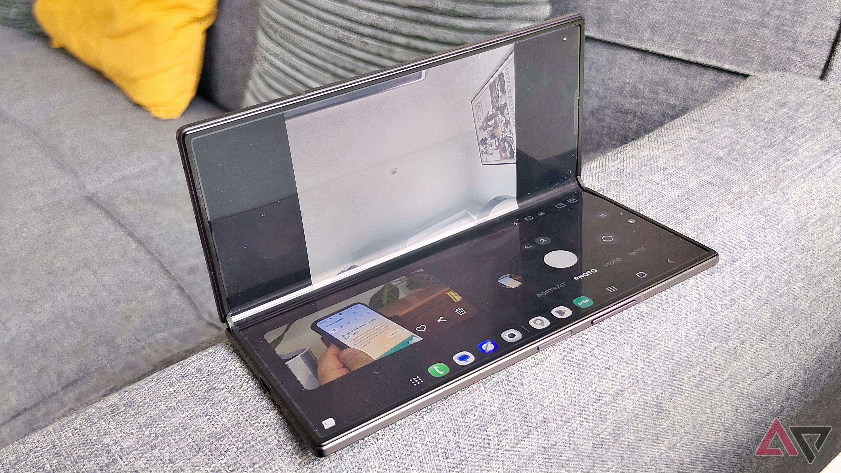 The Samsung Galaxy Z Fold 8 in Flex Mode on the arm of a sofa, showing the camera viewfinder.