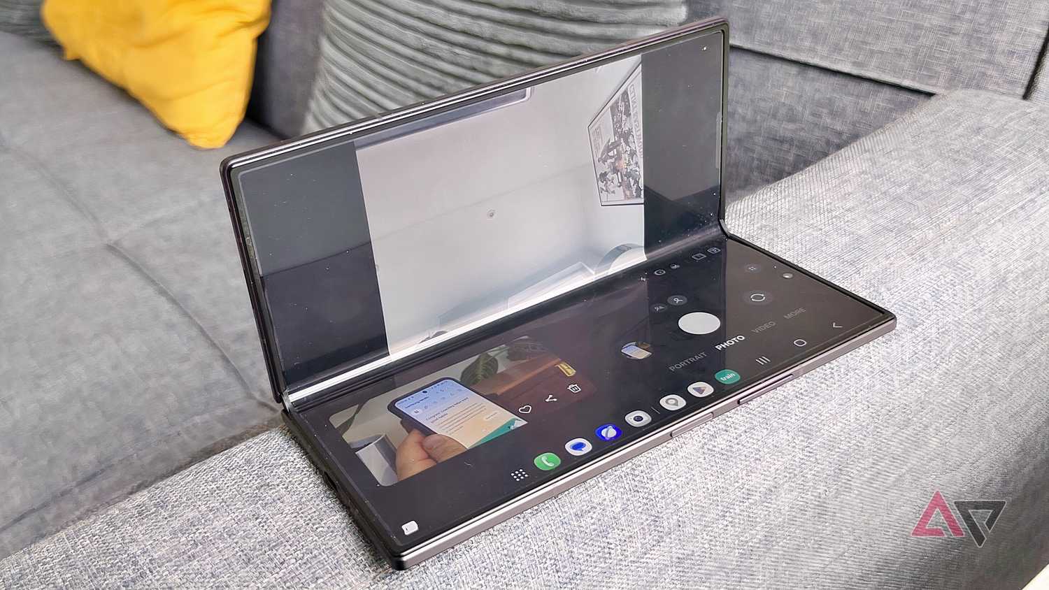 The Samsung Galaxy Z Fold 8 in Flex Mode on the arm of a sofa, showing the camera viewfinder.