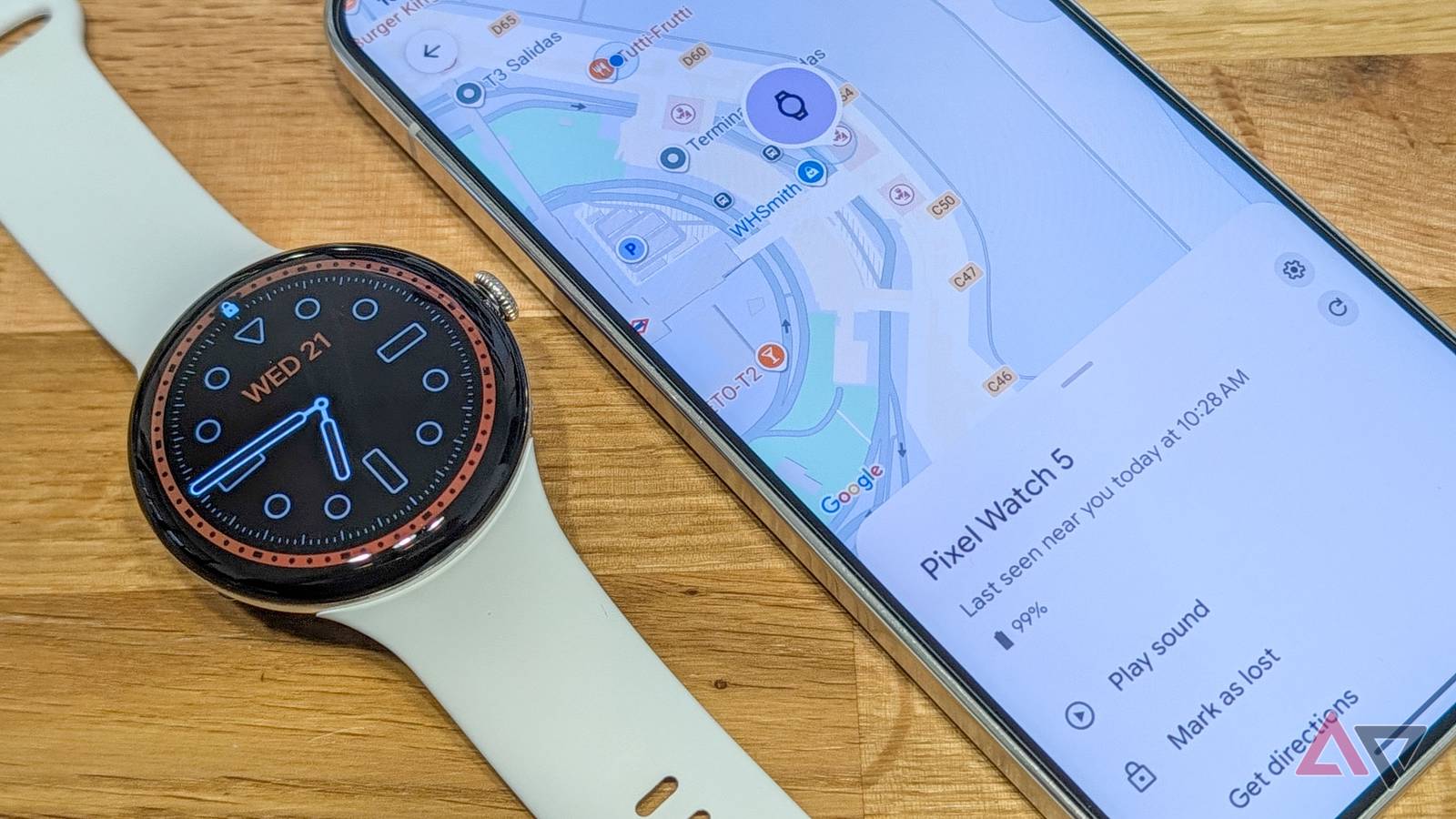 Google Pixel Watch next to phone, showing the Find Hub app and watch's location