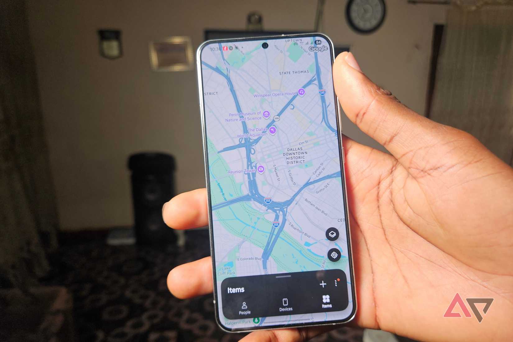 Hand holding a Samsung Galaxy phone showing the Samsung Find map of downtown Dallas with the Items tab open